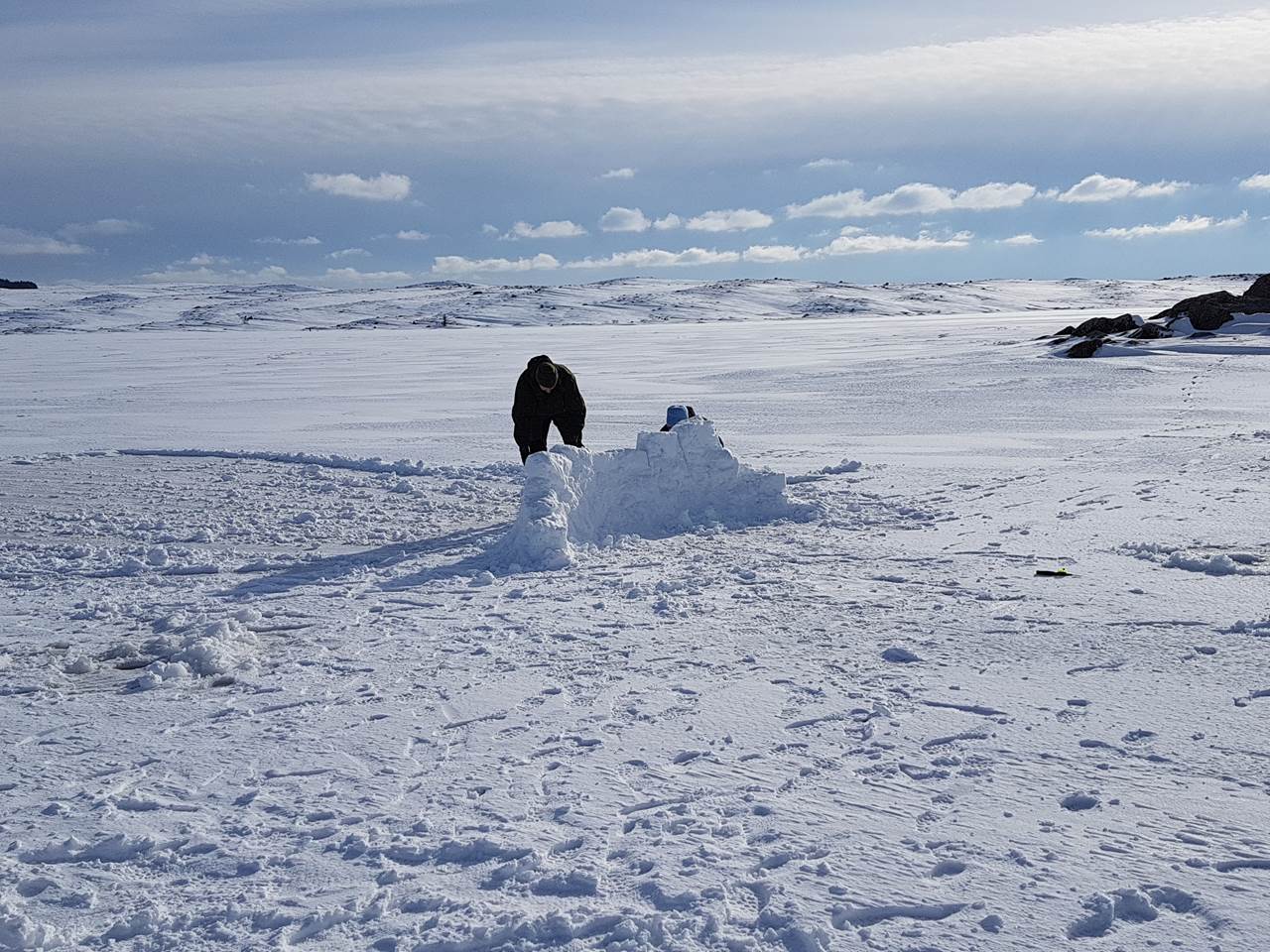Mann lager snøkuber og bygger mur på en frossen innsjø.