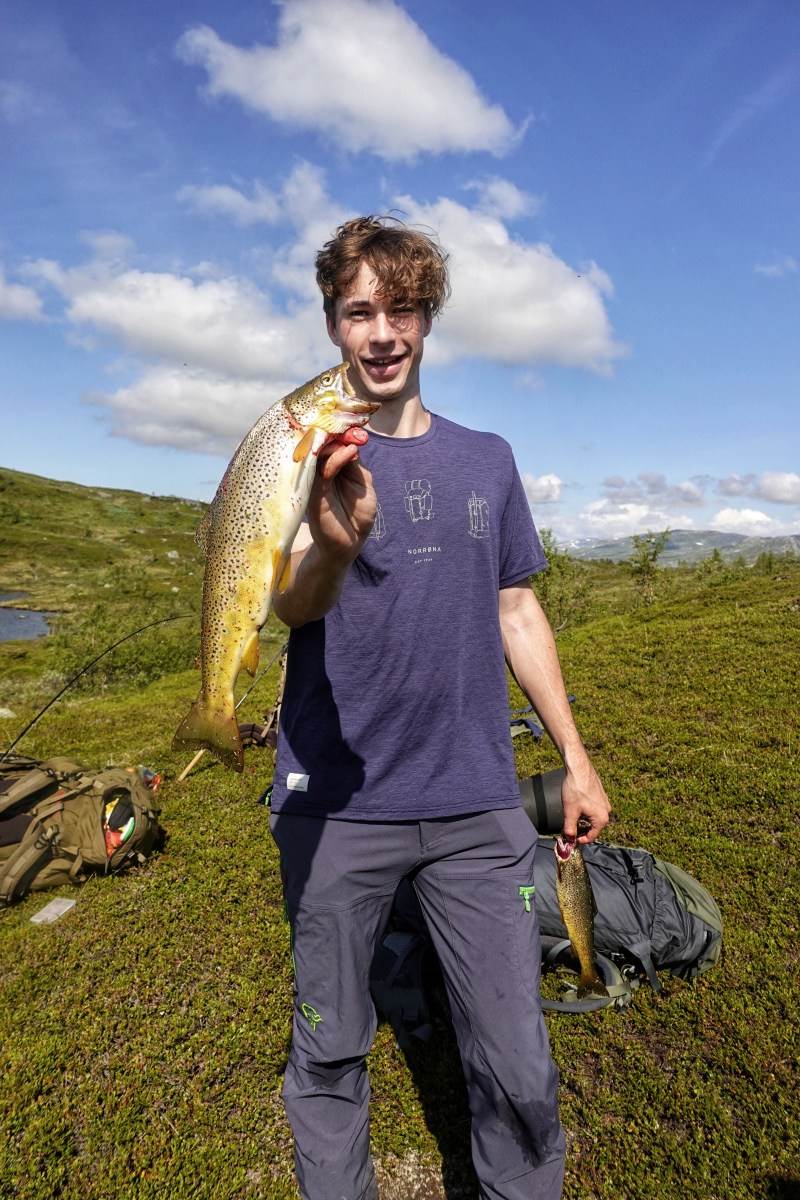 Ung mann som holder en 700 gram ørret i høyre hånden og viser den frem